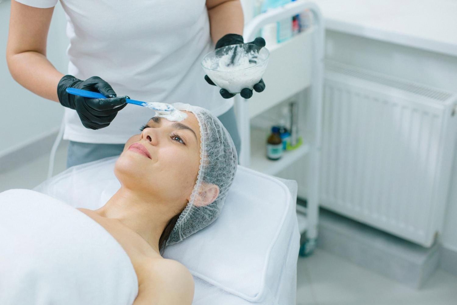 Aesthetician applying a mesotherapy mask to a woman's face in a Dubai cosmetic clinic